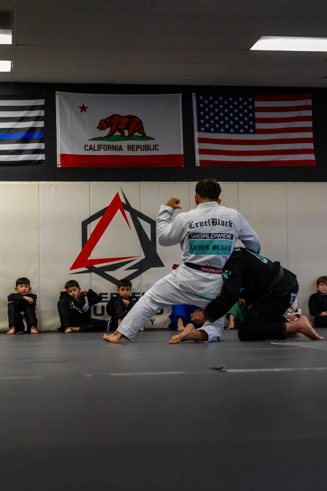 Instructor demonstrating a takedown to the kids class at Peerless Jiu Jitsu Academy in Corona, CA