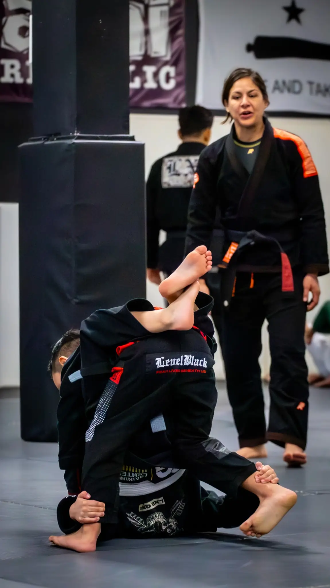 Coach guiding a young student through a drill at Peerless Jiu Jitsu Academy in Corona, CA