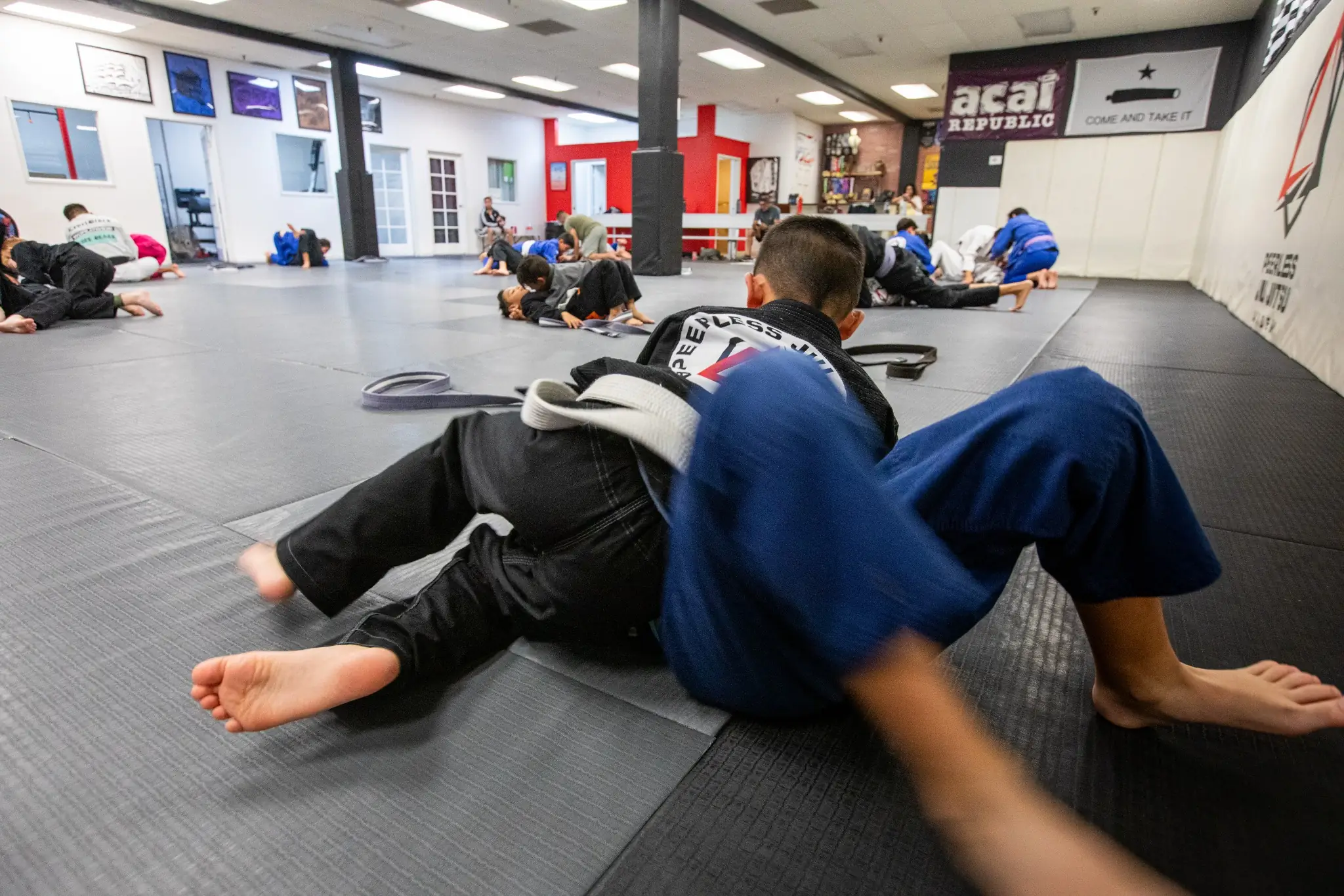 Adults rolling during training on the mats at Peerless Jiu Jitsu Academy in Corona, CA